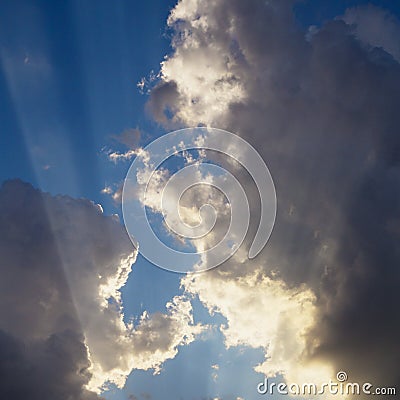 Rays of sunlight crossing a blue cloudscape sky Stock Photo