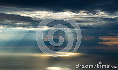 Rays of sunlight make their way through the clouds, illuminating the sea. Stock Photo