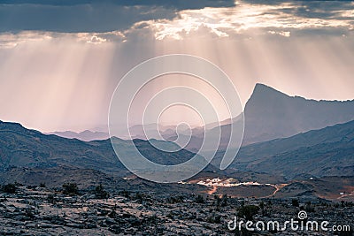 Rays of sunlight shine through scattered clouds on a small arabian village in Jebel Shams mountains, Oman. Epic sunlight Stock Photo