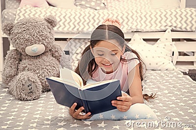 Read fairytale in bed. Girl child lay bed with teddy bear read book. Kid prepare to go to bed. Time for evening Stock Photo