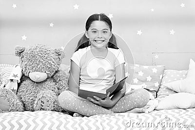 Read fairytale before go to bed. Girl child sit bed with teddy bear read book. Kid prepare to go to bed. Pleasant time Stock Photo