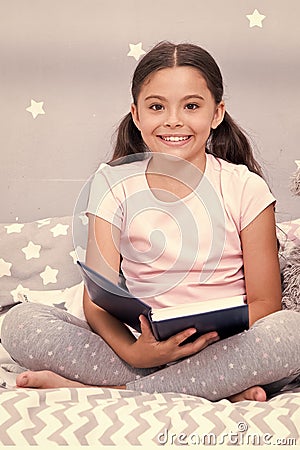 Read fairytale before go to bed. Girl child sit bed with teddy bear read book. Kid prepare to go to bed. Pleasant time Stock Photo