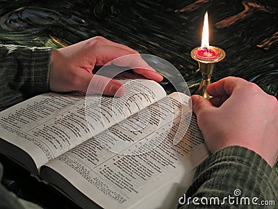 Reading Bible by candlelight Stock Photo