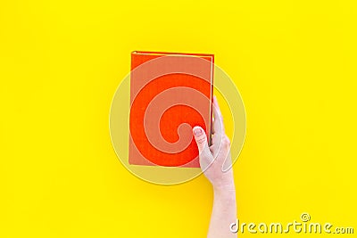 Reading concept. Reading as hobby. New knowledge. Hands take hardback book with empty cover on yellow background top Stock Photo