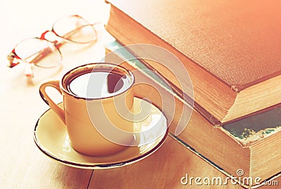 Reading glasses, stack of old books and smartphone over wooden table, retro filtered image Stock Photo