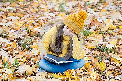 Reading really matters. Little child read book sitting on fall leaves. School library. Knowledge and informaiton Stock Photo