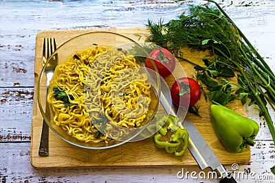 Ready noodles with vegetables and herbs on a wooden board. Stock Photo