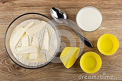 Ready flour mixture with butter for muffins in bowl, spoon, silicone molds, cup of milk on table. Top view Stock Photo