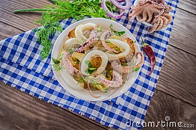 Ready fresh squid rings and tentacles of an octopus with stewed potatoes greens in rustic. Top view. Close-up Stock Photo