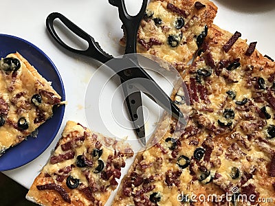 Ready pizza, cut into slices. Nearby there are scissors. Stock Photo