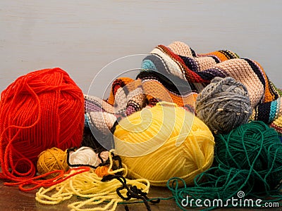 Wool image, with colorful knitted blanket and skeins of red, yellow and green wool Stock Photo