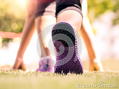 Ready steady go. Closeup of running shoes on grass, young lady on start position and going to run in park. Stock Photo