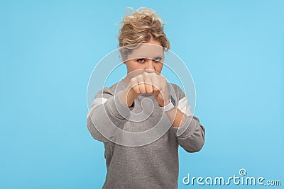 Ready to fight! Feisty woman with short curly hair in sweatshirt punching in front of camera, attacking and looking aggressively Stock Photo