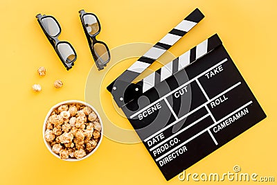 Ready to watch film. Clapperboard, glasses and popcorn on yellow background top view Stock Photo