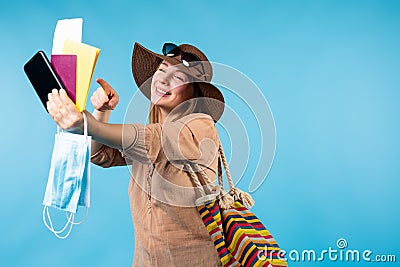 Ready for vacation in covid 19 pandemic. Holiday trip. Blonde smiling woman showing forefinger to passport, flight Stock Photo