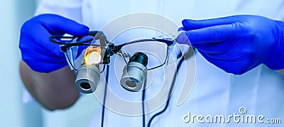 Real dental doctor holds the medical glasses with binocular lenses, in dentistry clinic. Dentist glasses or dental optic on a Stock Photo