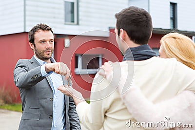 Real estate agent delivers keys to young atractive couple Stock Photo