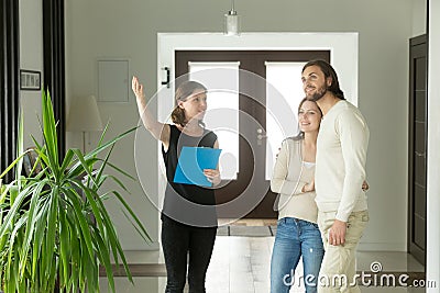 Real estate agent or designer showing house to young couple Stock Photo