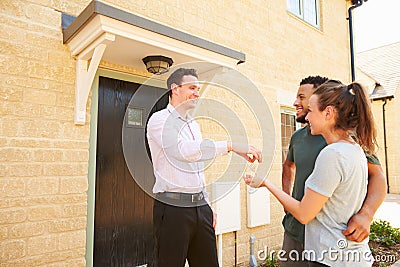 Real estate agent giving house keys to new property owners Stock Photo