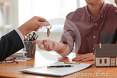 Real estate agent giving key from new house to man in office Stock Photo