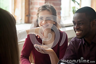 Real estate agent handing house keys to happy multiethnic couple Stock Photo