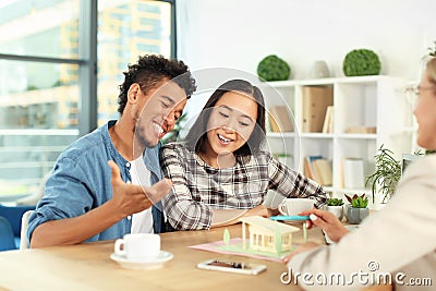 Real estate agent showing model of house to clients in her office Stock Photo