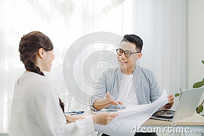 Real-estate agent shows a build project on a digital tablet to young Asian man Stock Photo