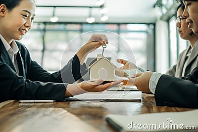 Real estate agents holding model house and keys for submit documents for customers to sign for a sale contract,real estate concept Stock Photo