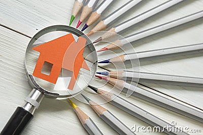 Real estate concept - magnifying glass, pencils and model house on wooden table. Stock Photo