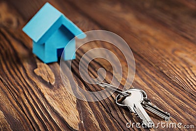 Real estate concept with small blue toy paper house and key on wooden background. Idea for real estate concept, personal propert Stock Photo