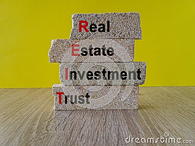 Real estate investment trust symbol. Concept red words Real estate investment trust on brick blocks on beautiful yellow background Stock Photo
