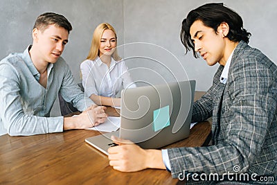 Real estate male agent in formal wear make offer for couple selects housing options, showing services presentation on Stock Photo