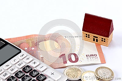 Real estate and mortgage concept: toy house, euro bill, coins and a calculator on white background with copy space for yo Stock Photo