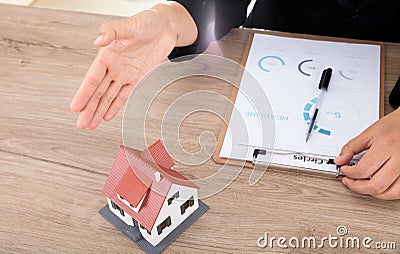 The real estate salesperson is pointing to the small house model to introduce to others Stock Photo