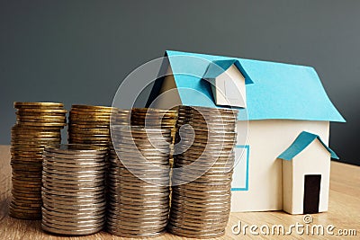 Real estate value. Model of house and stacks of coins. Stock Photo