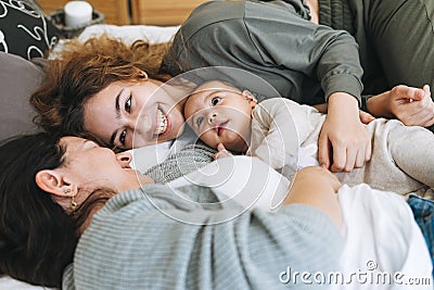 Real family of young mom and two kids of different ages teenager girl and baby boy having fun on the bed Stock Photo