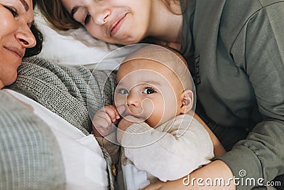 Real family of young mom and two kids of different ages teenager girl and baby boy having fun on the bed Stock Photo