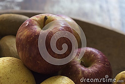 A real organic red apple with other fruits in a wooden tray Stock Photo