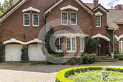 Real photo of a brick house with a bay window, garages and round Stock Photo