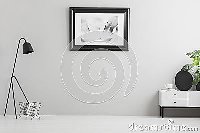 Real photo of bright grey living room interior with simple poster, metal lamp, white cupboard and empty place for your couch Stock Photo