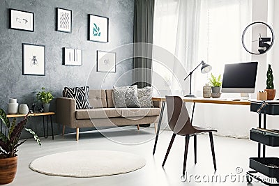 Real photo of a bright home office interior with a sofa, graphic Stock Photo