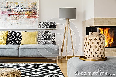 Real photo of a couch with pillows standing next to a lamp and b Stock Photo