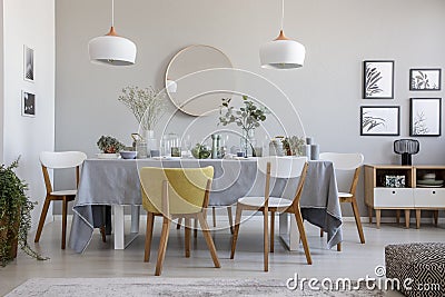 Elegant dining room interior with a laid table, chairs, mirror on a wall and lamps Stock Photo