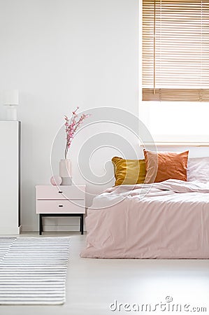 Real photo of a feminine bedroom interior with pink sheets on a Stock Photo