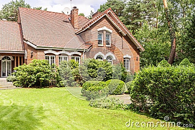 Real photo of garden with bushes and beautiful brick house Stock Photo