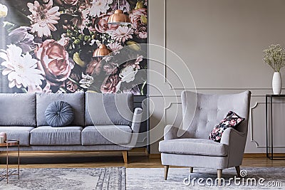 Real photo of a grey living room interior with a sofa, armchair, wallpaper and wall molding Stock Photo