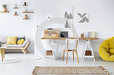 Modern home office interior with graphics, desk, sofa and yellow pouf Stock Photo