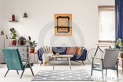 Real photo of a navy blue sofa with orange cushions and an artwo Stock Photo