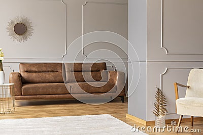 Open space flat interior with leather brown couch, molding on walls, white carpet and gold decor Stock Photo