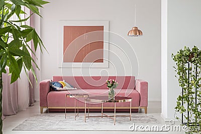 Real photo of a pink couch, round coffee tables and painting in a modern living room interior Stock Photo